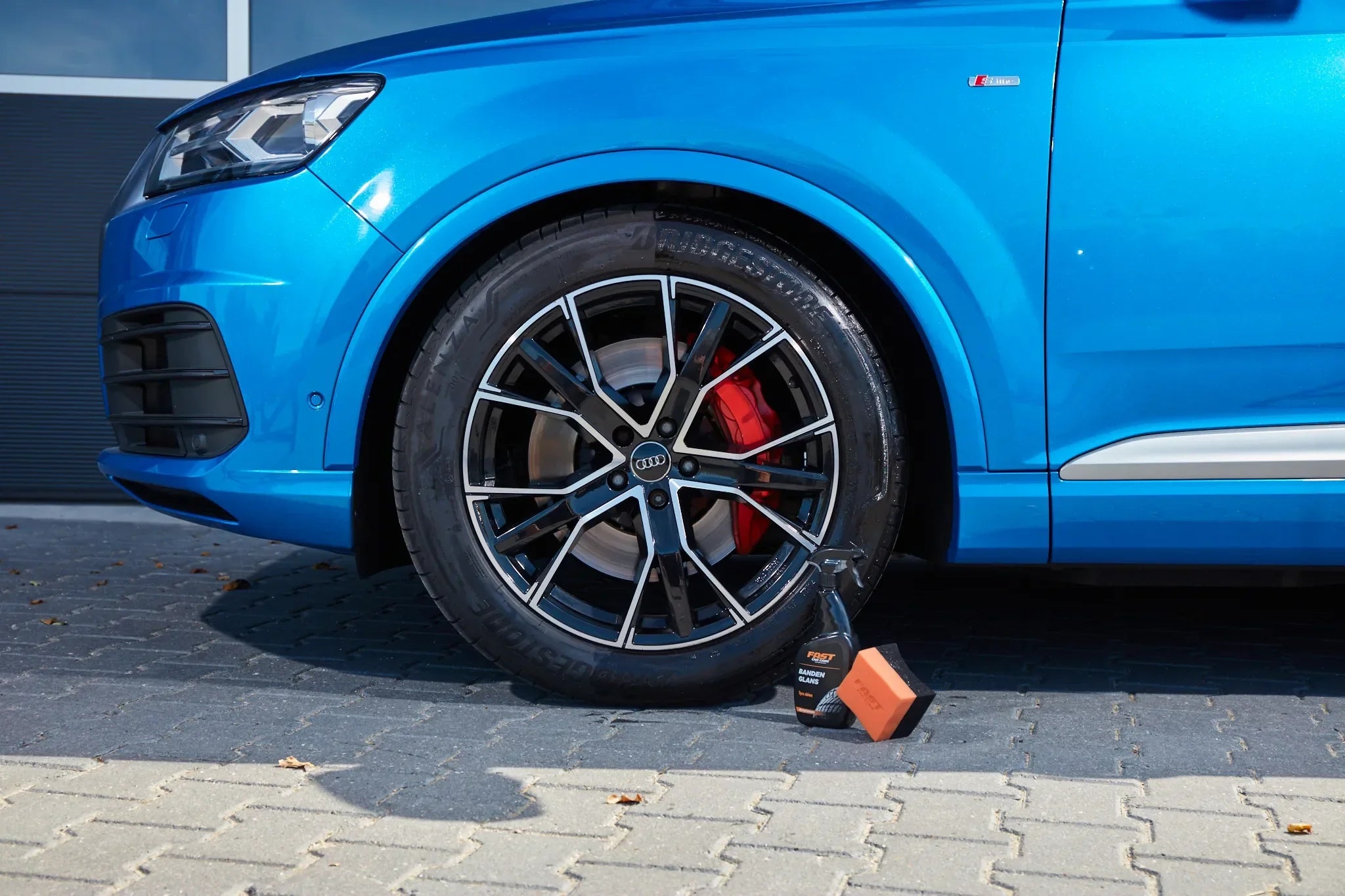 ast Car Care banden- en velgenreiniger – blauwe Audi met glanzende velgen en rode remklauw – professionele autoverzorging in zonlicht